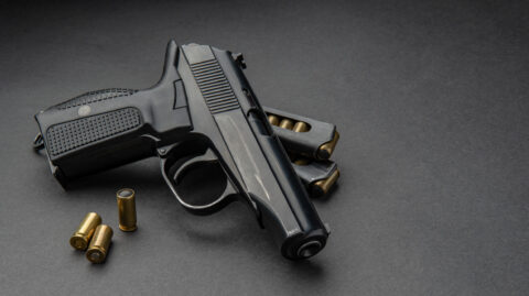 A gun laying on table with two bullets next to it