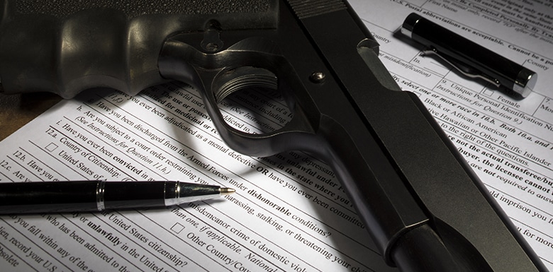 Black gun resting on blank firearm registration form