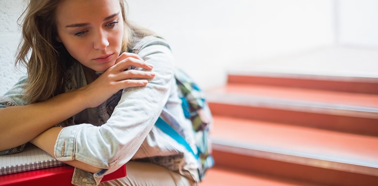 College student sitting on stairs looking helpless