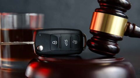 Gavel next to car key with alcohol in the background