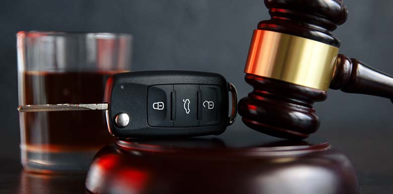 Gavel next to car key with alcohol in the background