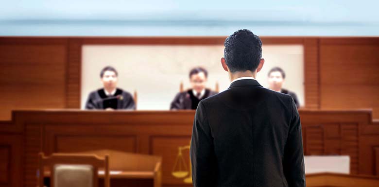 Man in suit speaking to a panel of three judges