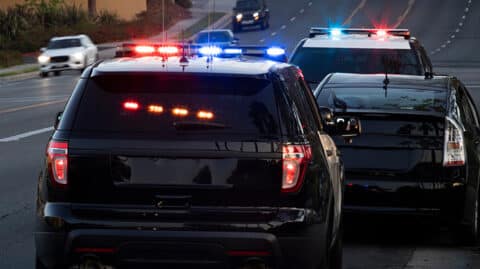 Two police vehicles parked next to first-time OVI offenders car on side of multilane road