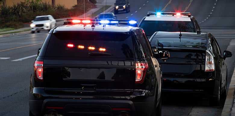 Two police vehicles parked next to first-time OVI offenders car on side of multilane road